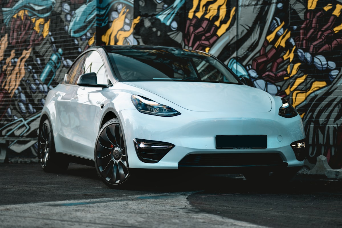 A white Tesla Model Y against a brightly painted wall